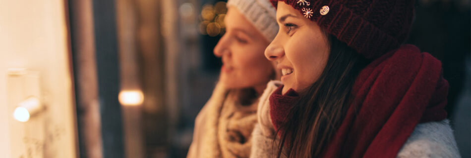 two women looking through store window in winter